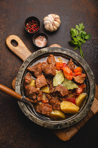 Meat beef stew with vegetables and gravy in rustic metal pot top view - Photo, Image