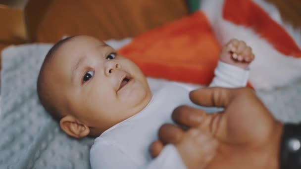 Baby first christmas. Papa und Neugeborenes spielen umgeben kaufen rote Geschenkboxen und Weihnachtsmütze - Filmmaterial, Video
