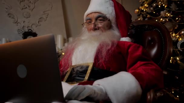 Close up moderno Babbo Natale utilizza laptop riempie i biglietti per le vacanze per i bambini - Filmati, video