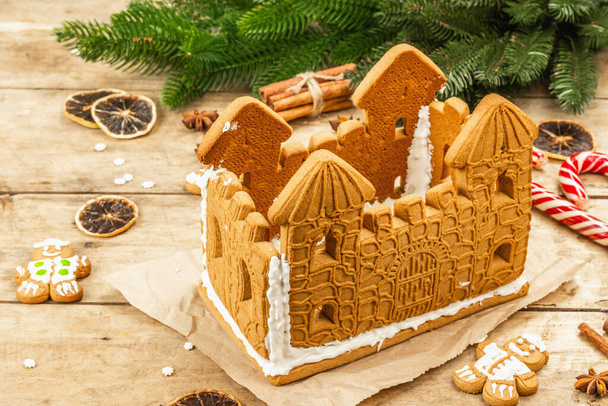 Lebkuchenhaus mit süßem Zuckerguss verziert. Handarbeit, festliches Neujahrsdekor. Traditionelle Gewürze, hölzerner Hintergrund - Foto, Bild