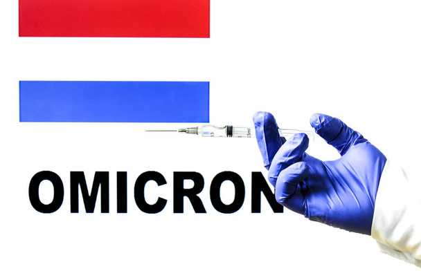 Kézi fecskendő kovid vakcinával. Holland zászló és Omicron kovid változat szó írva a háttérben - Fotó, kép