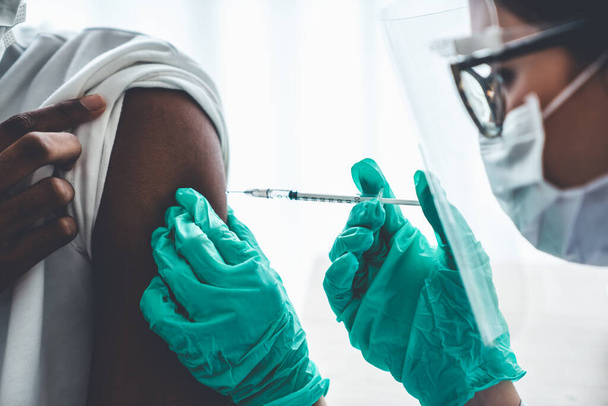 Νεαρός επισκέπτεται επιδέξιο γιατρό στο νοσοκομείο για εμβολιασμό - Φωτογραφία, εικόνα