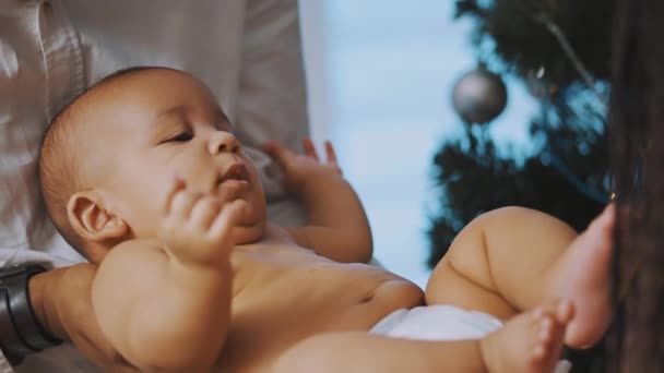 Baby first christmas. Papa und Neugeborenes spielen umgeben kaufen rote Geschenkboxen und Weihnachtsmütze - Filmmaterial, Video