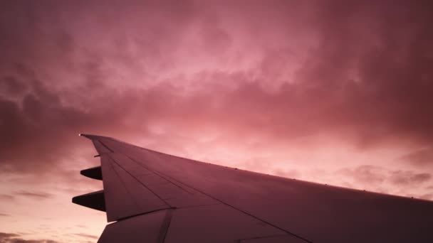 Close-up zicht op de wolken in roze lucht en vleugel van binnenuit gefilmd - Video