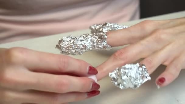 Preparing nails for manicure, fingers in foil. Selfmade manicure service. Manicurist paints nails with pink gel polish. Manicured red nails. Nail polish application. - Footage, Video