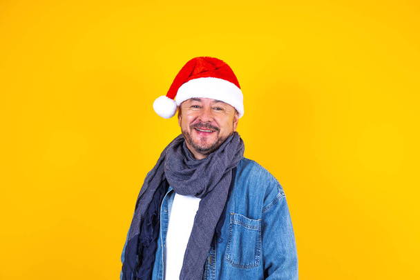 portret van Latijnse senior man met kerstmuts voor kerstfeest op gele achtergrond in Mexico Latijns-Amerika - Foto, afbeelding