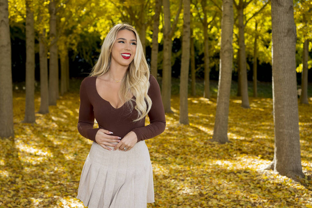 Ένα πανέμορφο ξανθό μοντέλο θέτει σε εξωτερικούς χώρους απολαμβάνοντας τον φθινοπωρινό καιρό - Φωτογραφία, εικόνα