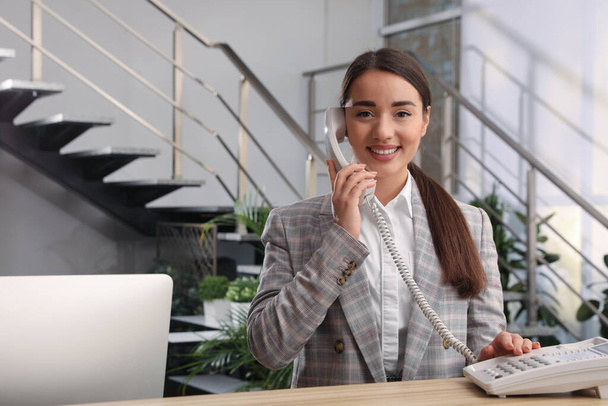Female receptionist talking on phone at workplace - Valokuva, kuva