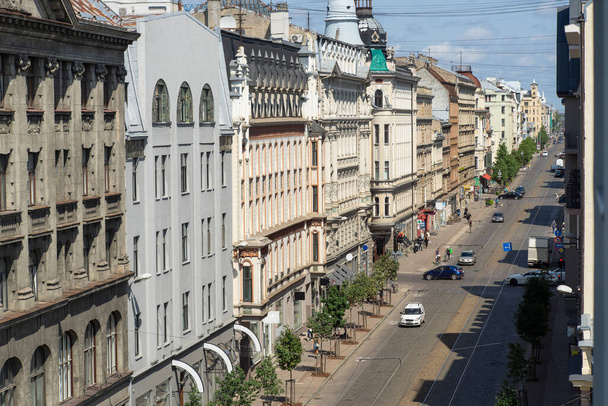 Scenic cityscape of Riga, Latvia. Top view of road with tramway. Parking cars. Green trees. Blue sky. - 写真・画像