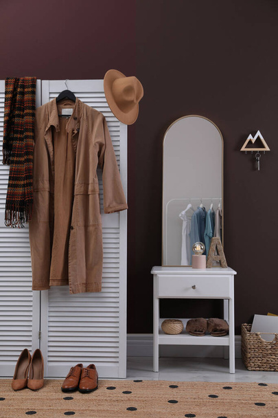 Modern hallway interior with stylish white furniture and wooden hanger for keys on brown wall - Fotó, kép