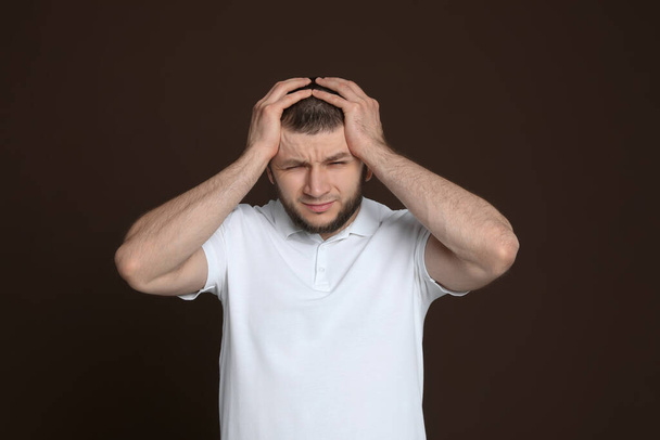 Man suffering from headache on dark brown background - Foto, immagini