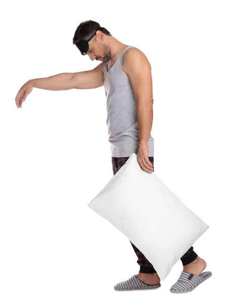 Man with pillow and eye mask in sleepwalking state on white background - Foto, afbeelding