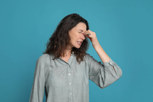 Mature woman suffering from headache on light blue background - Foto, Imagem