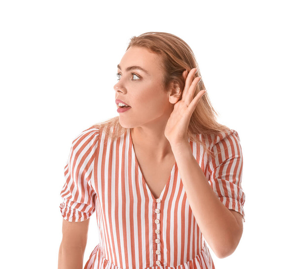 Neugierige junge Frau versucht, etwas auf weißem Hintergrund zu hören - Foto, Bild