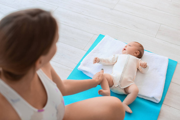 Junge schwangere Frau praktiziert Yoga mit ihrem kleinen Baby im Fitnessstudio - Foto, Bild