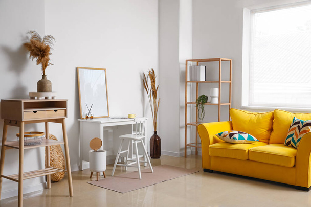 Şık oturma odasının içinde sarı kanepe, işyeri ve kuru sazlıklar. - Fotoğraf, Görsel