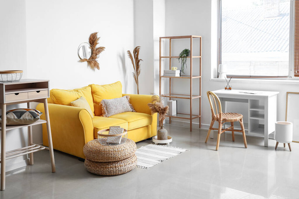 Intérieur du salon élégant avec canapé jaune, lieu de travail et roseaux secs - Photo, image