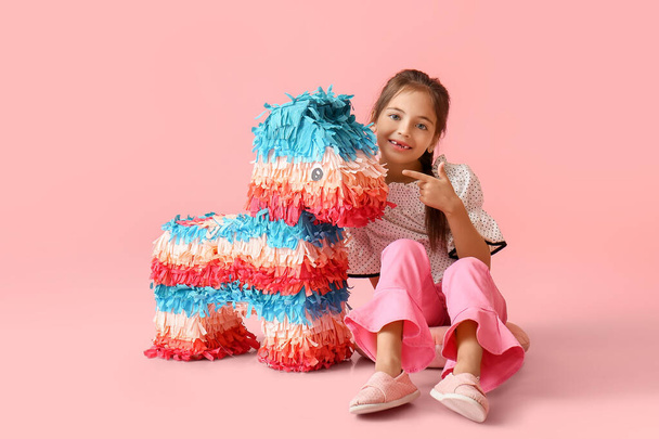 Niña apuntando a la piñata mexicana sobre fondo de color - Foto, Imagen