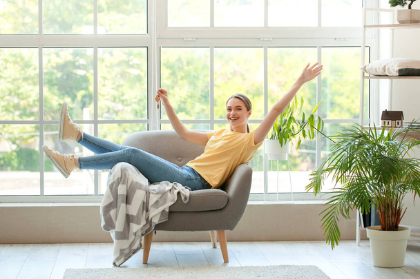 Ευτυχισμένη νεαρή γυναίκα με κλειδί κάθεται στο νέο της διαμέρισμα - Φωτογραφία, εικόνα
