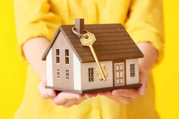 Mladá žena s modelem domu a klíčem na žlutém pozadí, detailní záběr - Fotografie, Obrázek