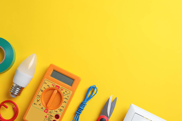 Flat lay composition with electrician's tools and accessories on yellow background, space for text - Photo, Image