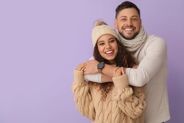 Happy hugging couple in winter clothes on color background - Foto, afbeelding