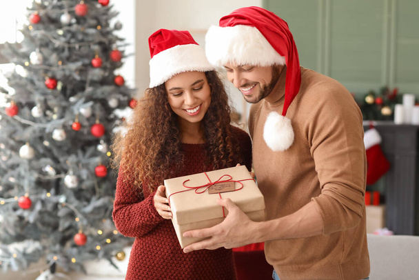 Happy couple with Christmas gift at home - Photo, Image