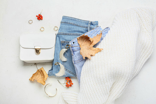 Jeans, sweater, stylish accessories and autumn decor on light background - Photo, Image