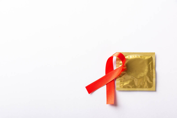 Símbolo vermelho da fita do arco HIV, consciência do câncer da AIDS e preservativo com sombras, estúdio isolado no fundo branco, conceito sexual da medicina de saúde, Dia Mundial da AIDS - Foto, Imagem