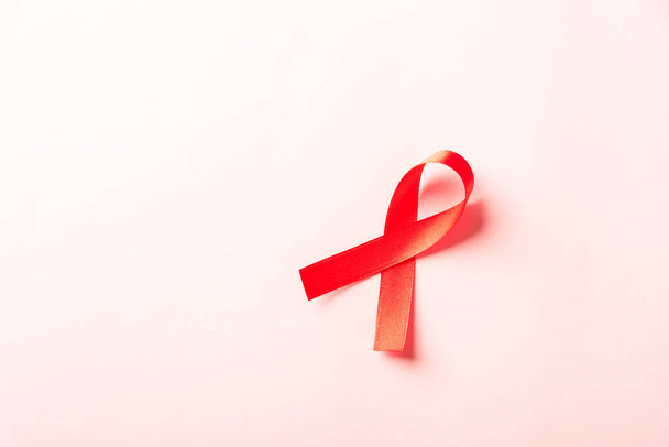 Fiocco rosso simbolo HIV, AIDS cancro consapevolezza con ombre, studio girato isolato su sfondo rosa, Concetto di medicina sanitaria, Giornata mondiale dell'AIDS - Foto, immagini