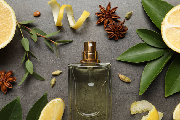 Flat lay composition with bottle of perfume and fresh citrus fruits on grey table - 写真・画像