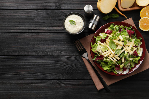Delicious turnip salad served on black wooden table, flat lay. Space for text - Foto, imagen