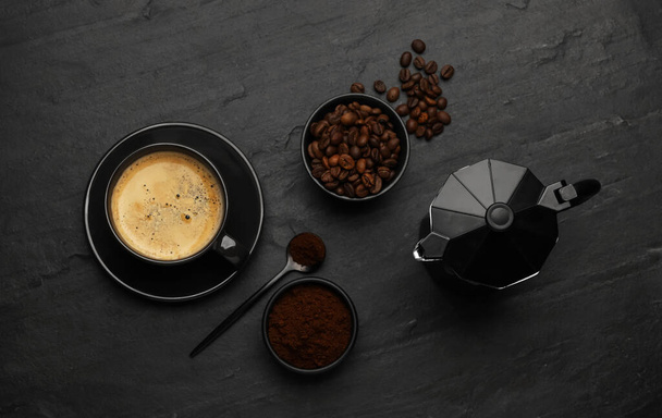 Flat lay composition with coffee grounds and roasted beans on black background - Фото, изображение