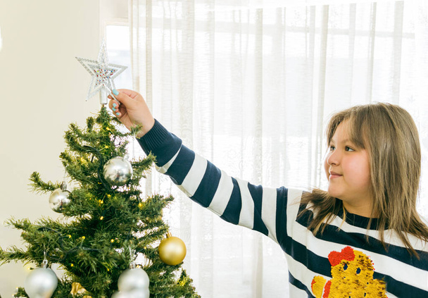 Menina loira hispânica colocando estrela na árvore de Natal - Foto, Imagem