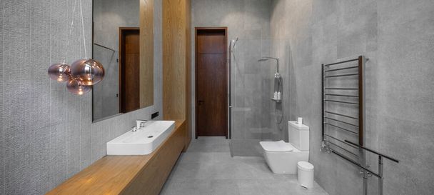 Intérieur de la salle de bain dans un appartement de luxe. Design gris et bois. Douche en verre. - Photo, image