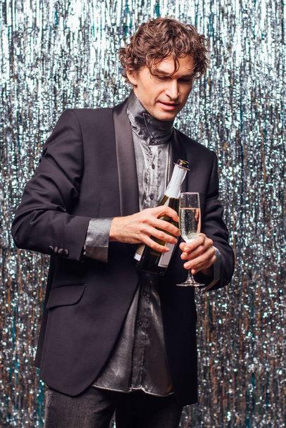 Holidays concept - happy tipsy man with bottle of champagne and wine glass at christmas or new year party on a sparkle background. - Foto, Bild