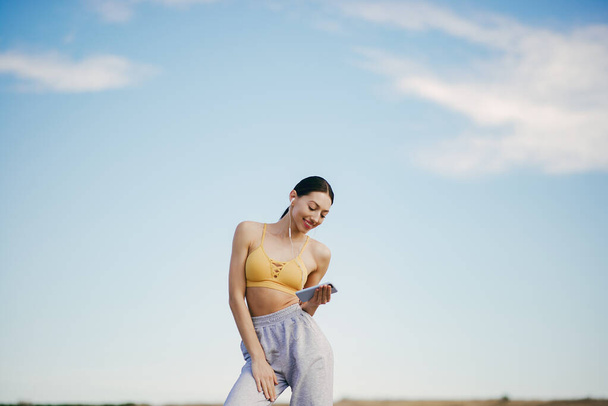 Cute girl with phone training on a sky backgroung - Foto, Bild