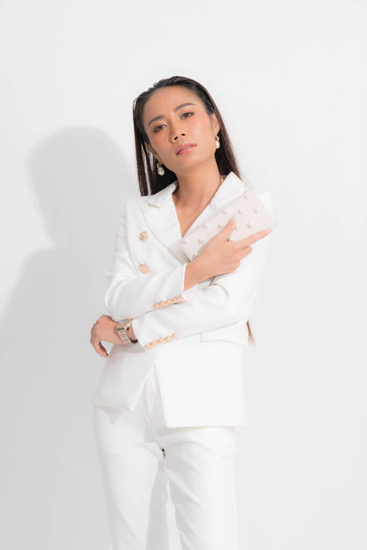 Fashion style catalog clothing for business woman black long hair natural make up wear white suit costume perfect body shape suit, carrying white bag at studio shoot on white background and shadow. - Foto, Imagem
