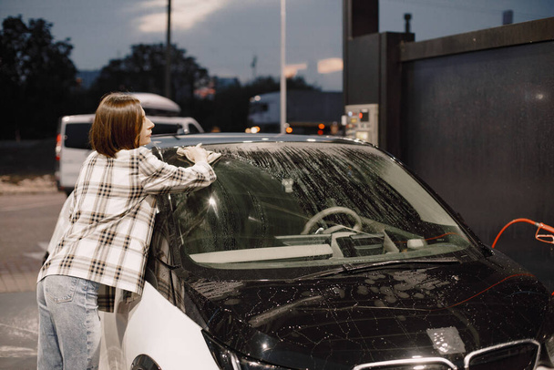 Woman washing her car with a rug in the car wash station - Foto, Imagen
