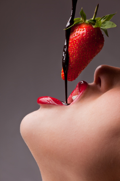 Mädchen isst Erdbeere mit Schokosauce - Foto, Bild