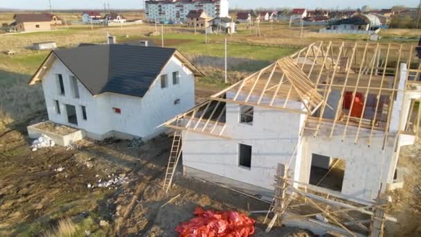 Havalandırılmış hafif beton duvarları ve yapım aşamasındaki ahşap çatı iskeleti olan bitmemiş özel evin havadan görüntüsü. - Video, Çekim