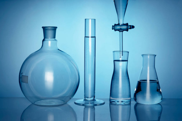 Fondo medico o chimico con apparecchiature di laboratorio e liquidi. Su sfondo blu, vista frontale. - Foto, immagini
