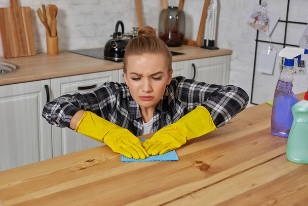 Młoda kobieta w rękawiczkach ochronnych wyciera stół w kuchni szmatą - Zdjęcie, obraz