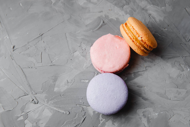 Gâteau coloré rose, orange, violet macaron français ou italien ou macaron sur fond gris béton. Espace de copie
 - Photo, image