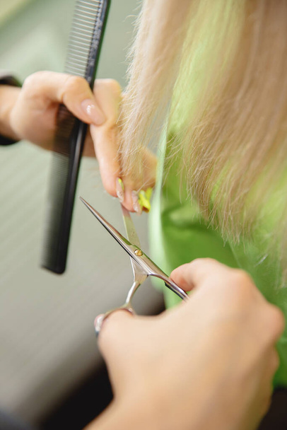 Primer plano de las tijeras de peluquería maestro con tijeras puntas secas de mujer cabello en el salón - Foto, imagen