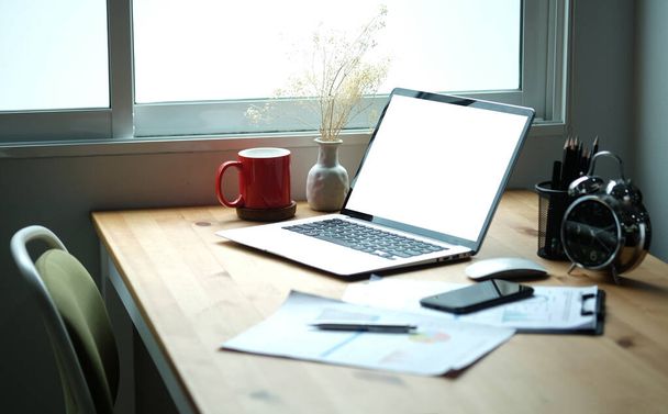 Computer portatile con schermo bianco, tazza di caffè, appunti e portapenne su scrivania in legno. - Foto, immagini