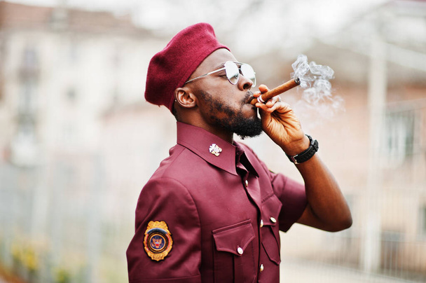 Portrait of African American military man in red uniform, sungalasses and beret. Captain smoke cigar. - Fotografie, Obrázek
