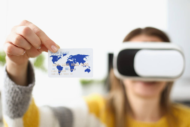 Jovem mulher usando óculos virtuais e mostrando cartão de crédito - Foto, Imagem