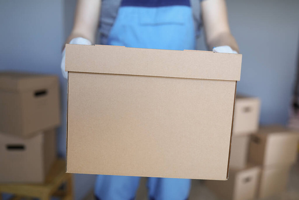 Εργαζόμενος φόρτωση χαρτονένια κουτιά με τους ιδιοκτήτες αντικείμενα στο νέο διαμέρισμα - Φωτογραφία, εικόνα