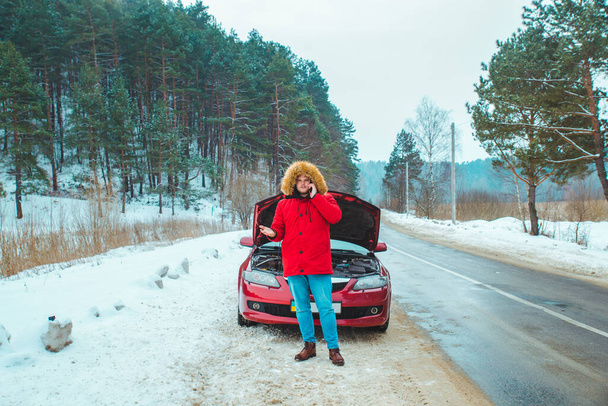 Mężczyzna stojący w pobliżu zepsutego samochodu przy śnieżnej pogodzie. przestrzeń kopiowania - Zdjęcie, obraz